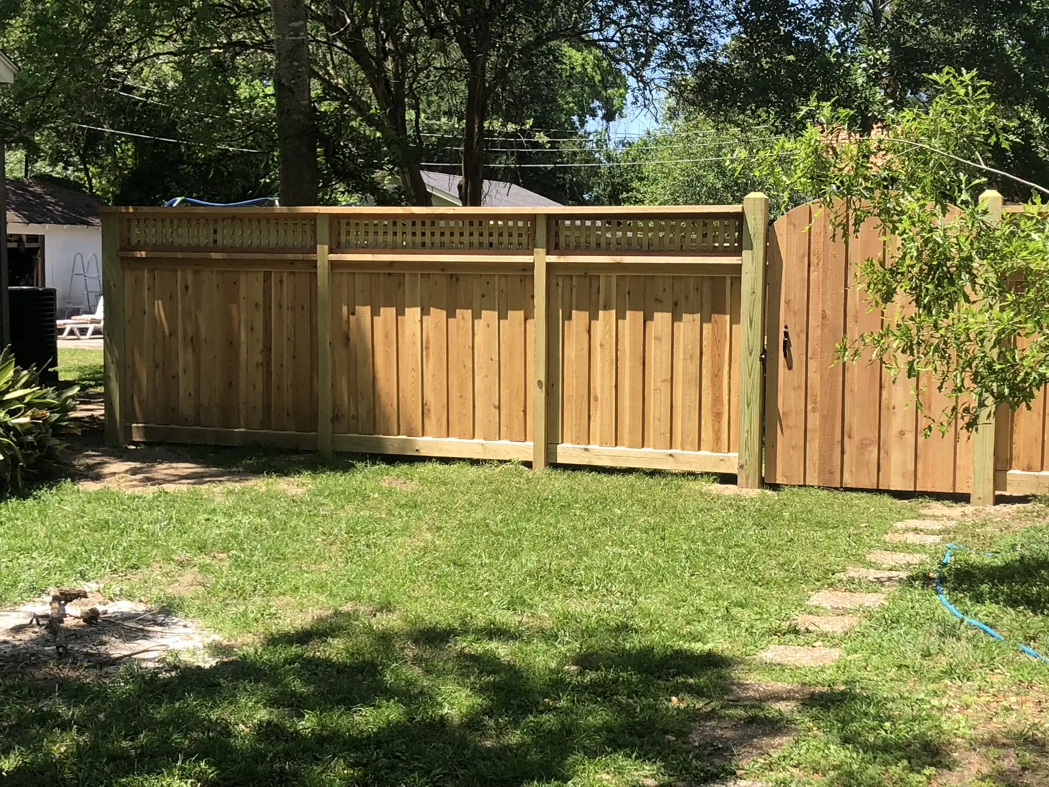 Cedar privacy fence panels with a lattice top band, running to an arched gate