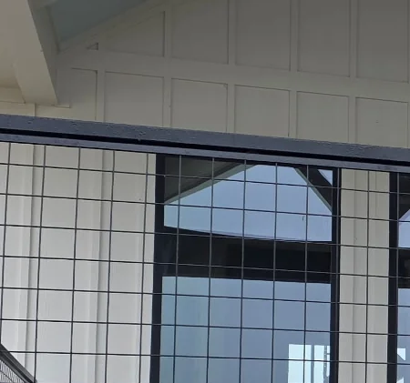 Wire panel railing along a covered deck