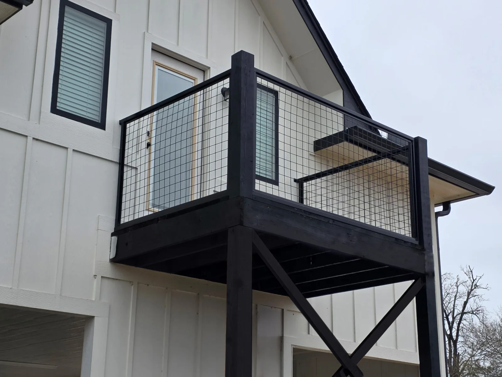 Elevated deck with a wire panel railing on a two-story home