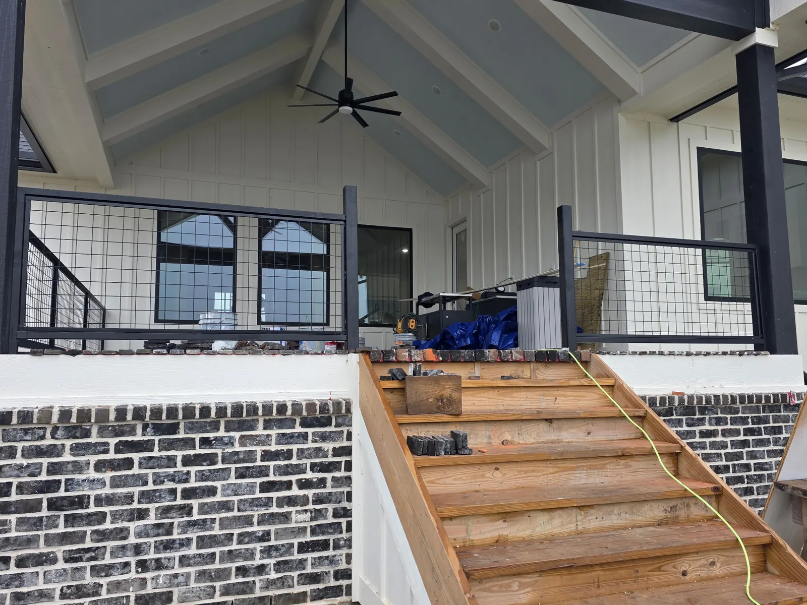 Covered deck with wire panel railings and new wood stairs under a vaulted ceiling