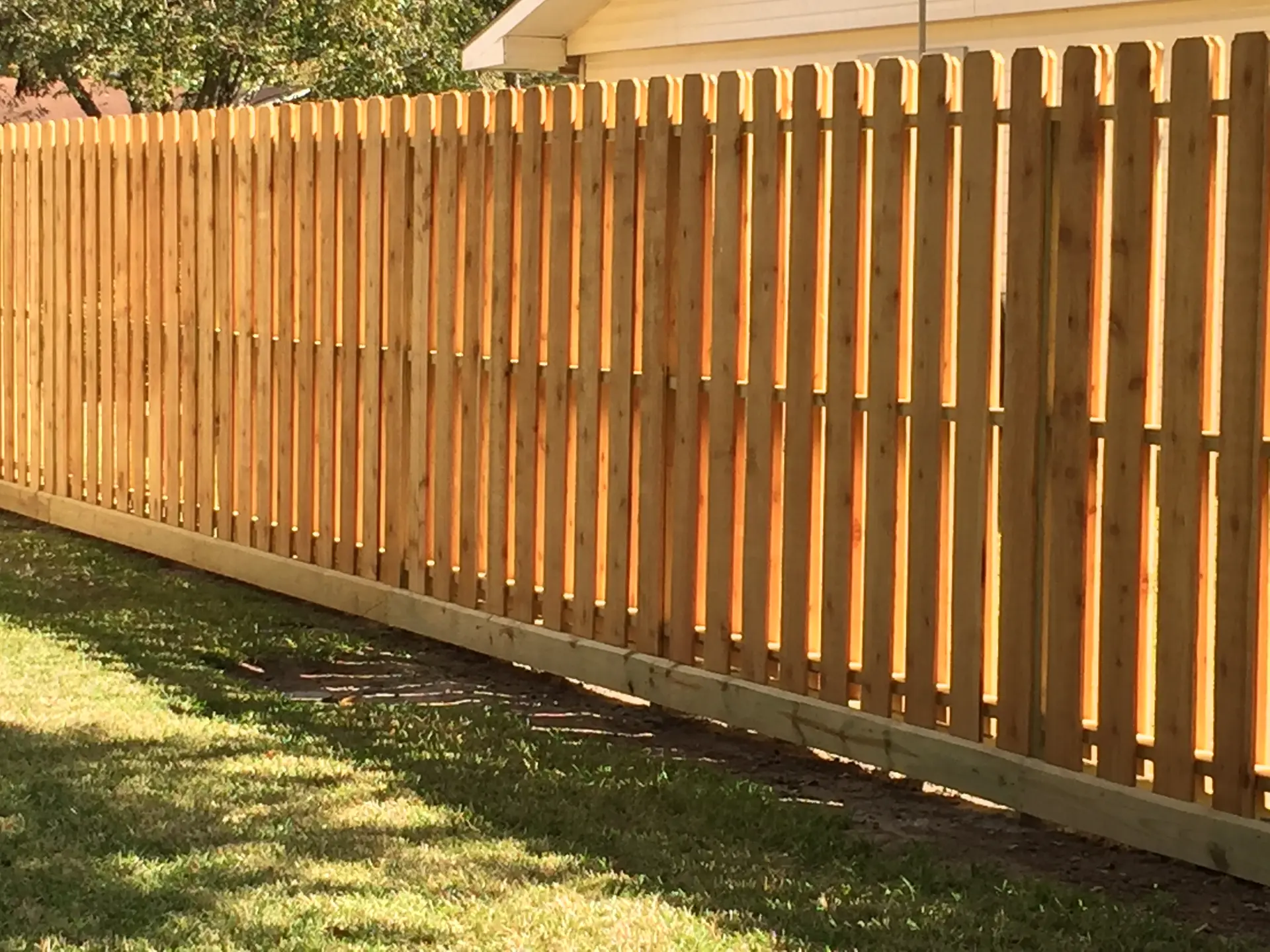 Wood picket fence running the length of a backyard