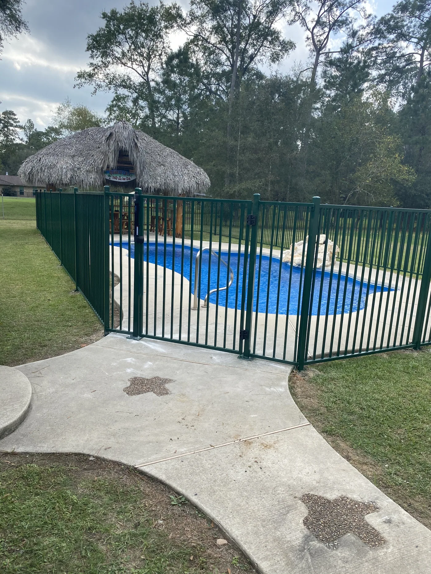 Pool safety fence with a self-latching gate around a backyard pool