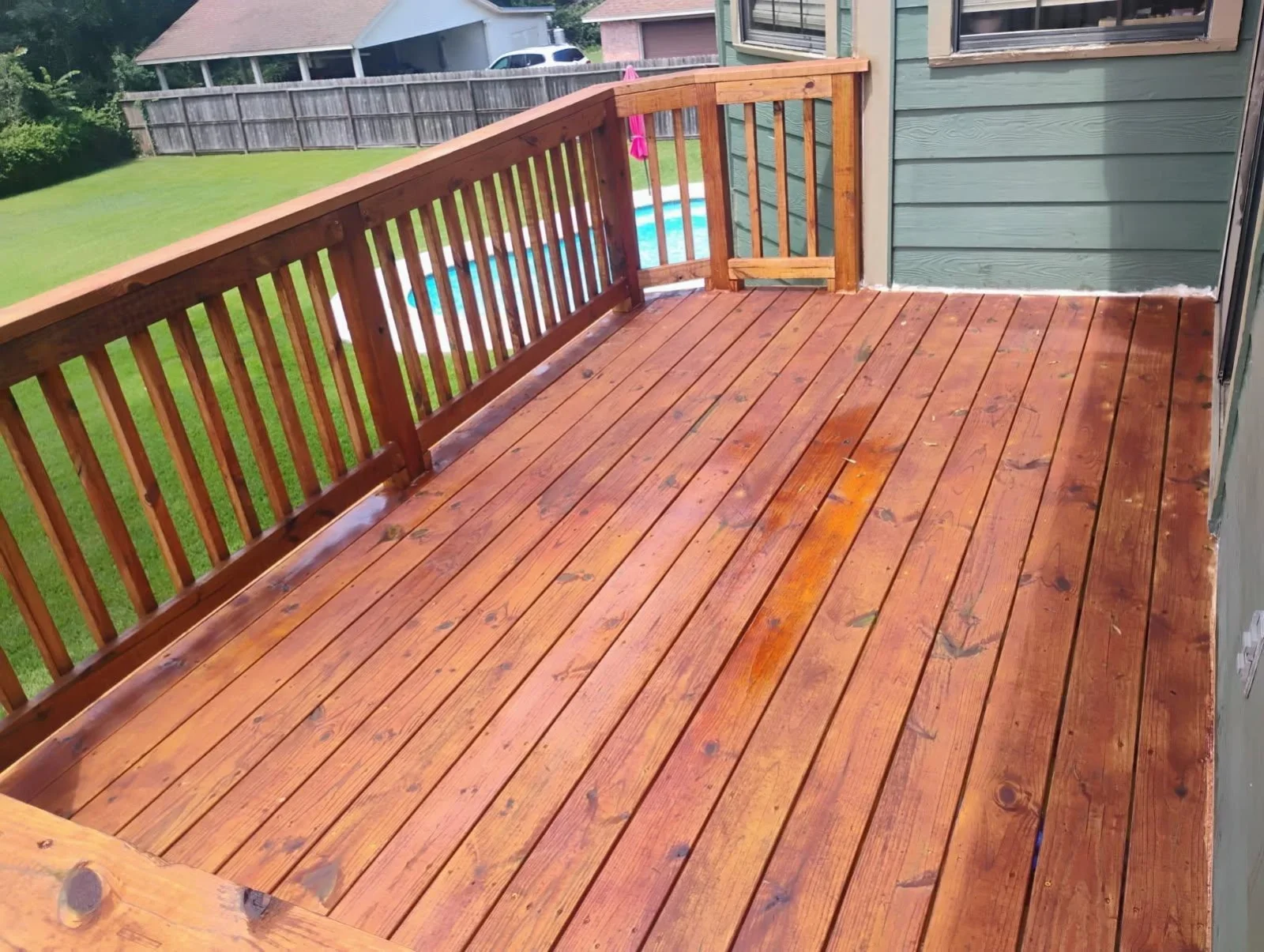 Stained wood deck overlooking a backyard pool