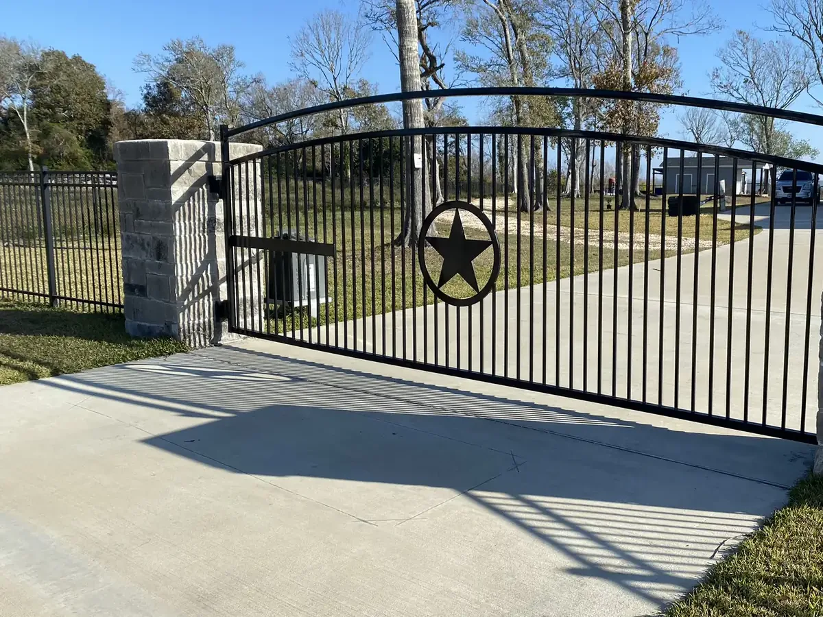 Arched driveway gate with an operator at the hinge post on a concrete drive