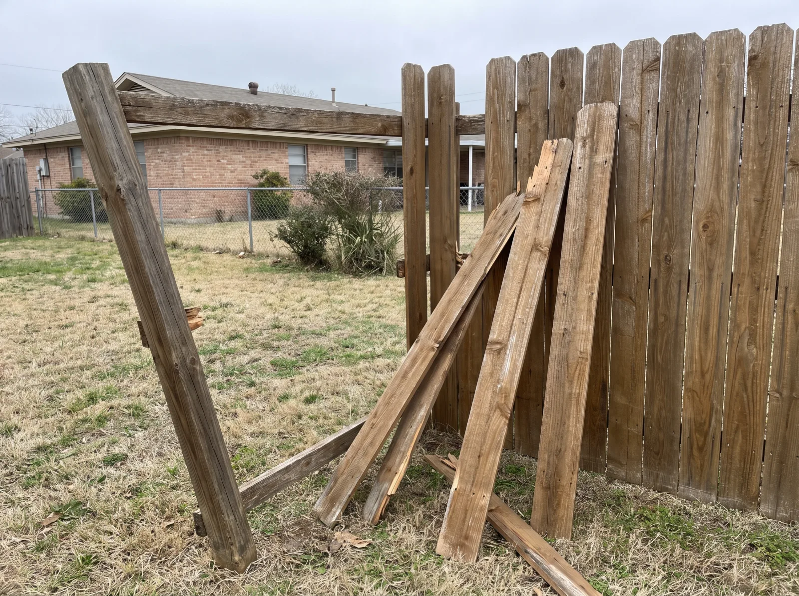 Fence repair needed on a wood privacy fence with broken pickets and a leaning post