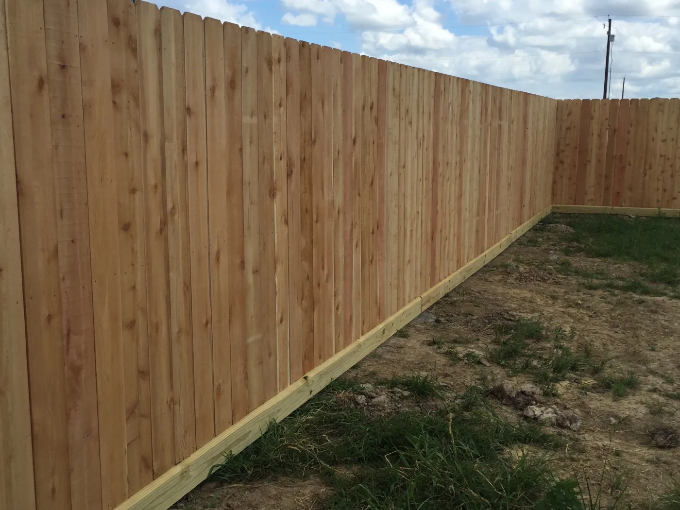 Wood privacy fence with dog-ear pickets along an open lot